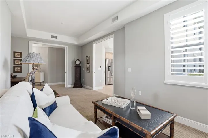 Living area with light colored carpet and a tray ceiling