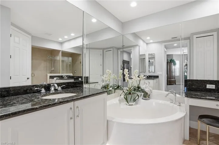 Bathroom with a closet, vanity, a tile shower, and a bath