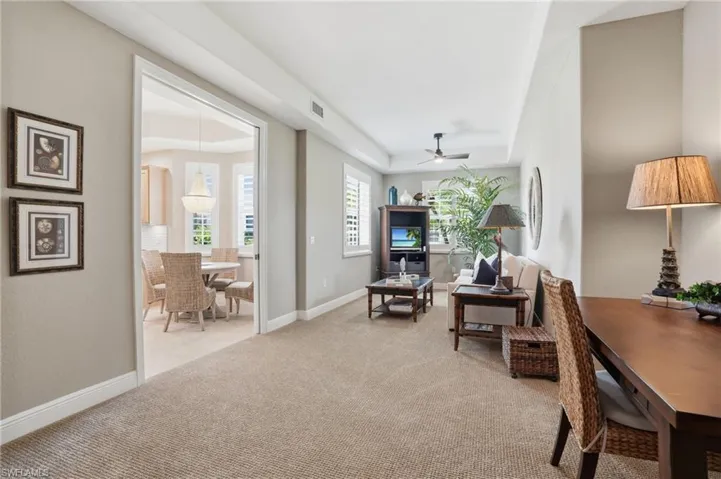 Living area featuring light carpet, ceiling fan, and a raised ceiling