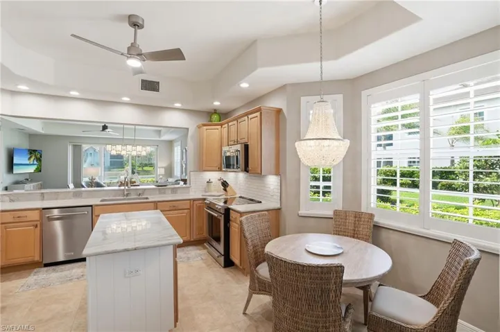 Kitchen with a chandelier, stainless steel appliances, decorative backsplash, light wood finish cabinetry, and a kitchen island