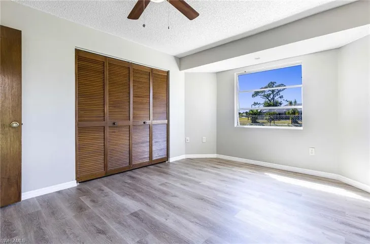 Unfurnished bedroom with ceiling fan, a closet, a textured ceiling, and wood-type flooring