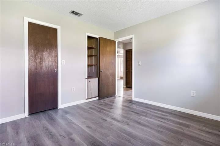 Unfurnished bedroom with dark wood-type flooring, a closet, and a textured ceiling