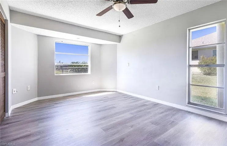 Empty room featuring hardwood / wood-style flooring, ceiling fan, and a textured ceiling