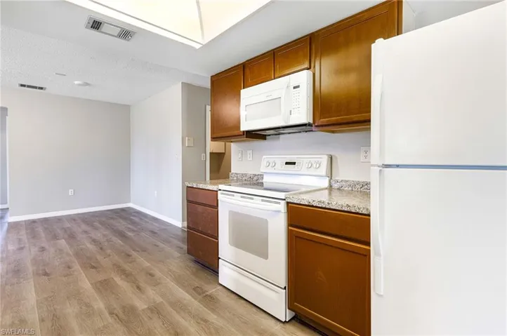 Kitchen featuring light hardwood / wood-style floors, a textured ceiling, and white appliances