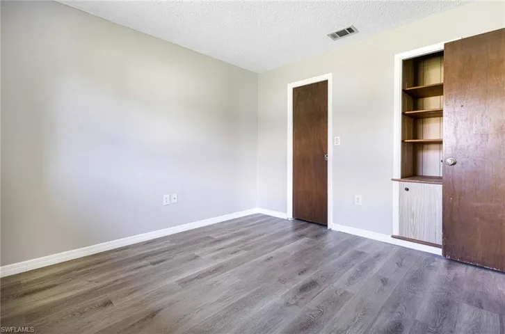 Unfurnished bedroom featuring hardwood / wood-style flooring and a textured ceiling