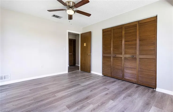 Unfurnished bedroom with hardwood / wood-style flooring, a closet, ceiling fan, and a textured ceiling