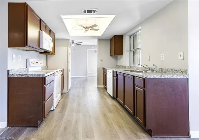 Kitchen featuring ceiling fan, sink, white appliances, and light hardwood / wood-style flooring