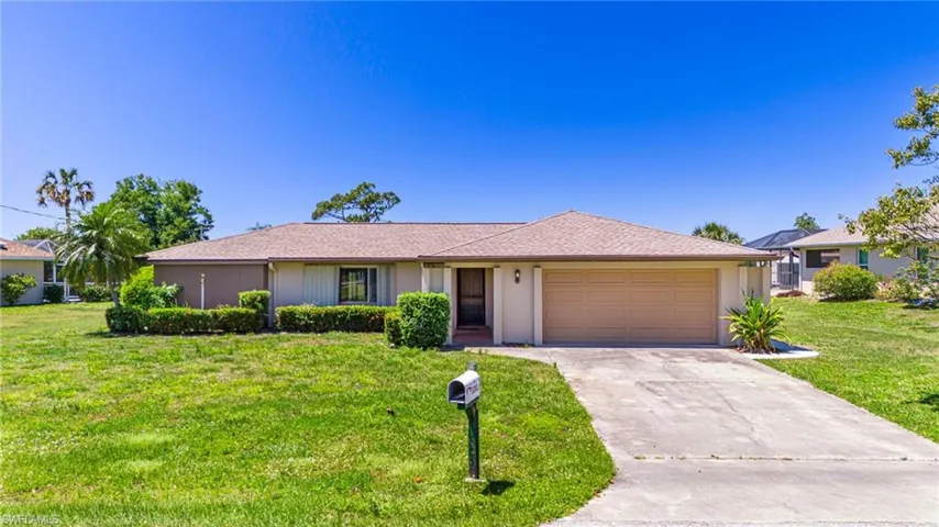 Ranch-style house featuring a garage and a front lawn