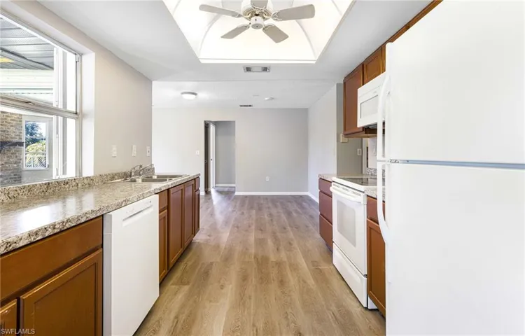 Kitchen featuring ceiling fan, sink, white appliances, and light hardwood / wood-style flooring