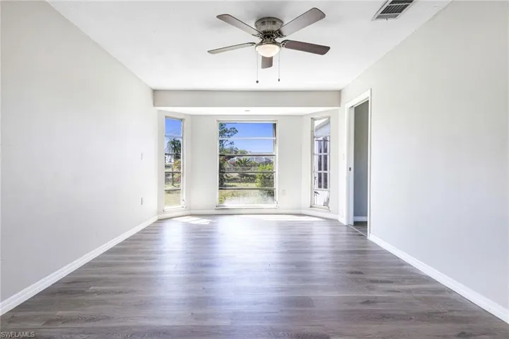 Unfurnished room featuring dark wood-type flooring and ceiling fan