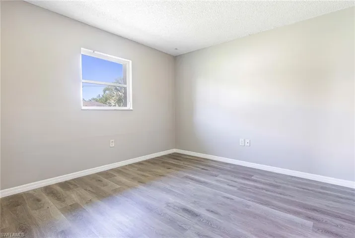 Unfurnished room with a textured ceiling and wood-type flooring