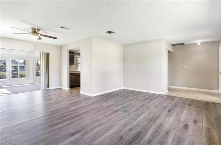 Unfurnished living room featuring a textured ceiling, wood-type flooring, and ceiling fan