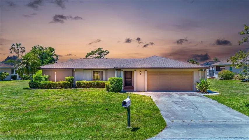 Single story home featuring a garage and a yard