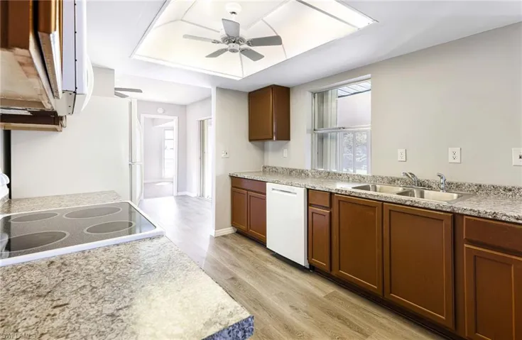 Kitchen with light hardwood / wood-style flooring, stove, ceiling fan, white dishwasher, and sink