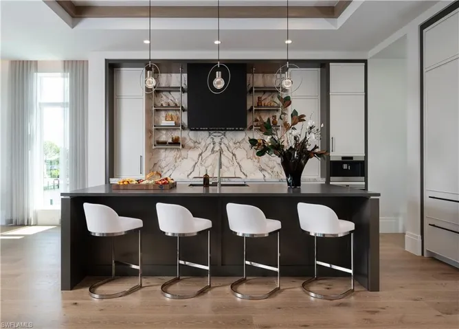 Contemporary kitchen featuring a dark island with a contrasting light countertop, a marble-patterned backsplash, and integrated appliances