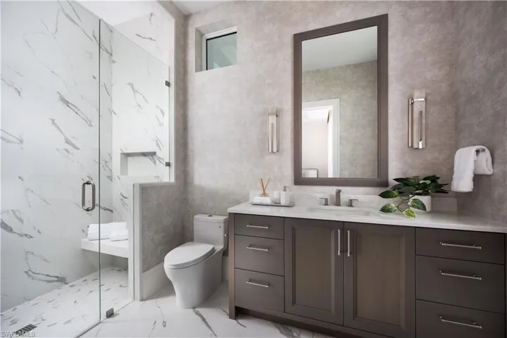 Contemporary bathroom featuring a spacious glass-enclosed shower with a built-in bench and recessed shelf