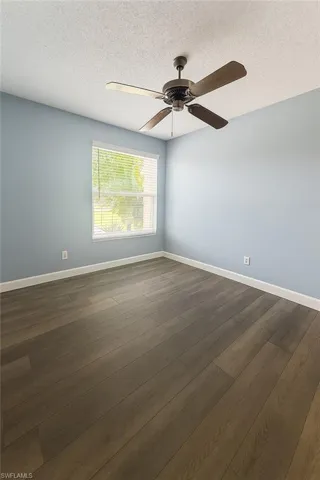 Spare room with a ceiling fan, dark LVP flooring, and a textured ceiling