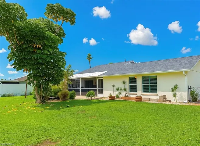 Rear view of house featuring stucco siding, a sunroom/lanai, and a shingled roof