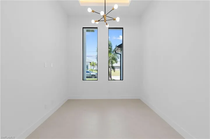 Unfurnished room featuring a chandelier and a tray ceiling