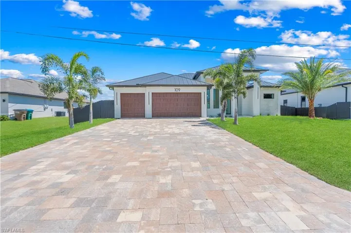 View of front of property featuring an attached garage, driveway, and stucco siding
