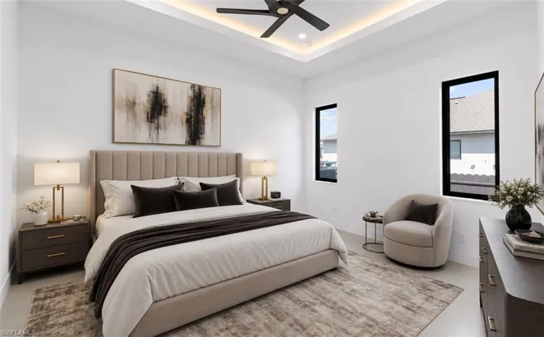 Spacious bedroom featuring clean white walls, a tray ceiling with recessed lighting, and a modern ceiling fan
