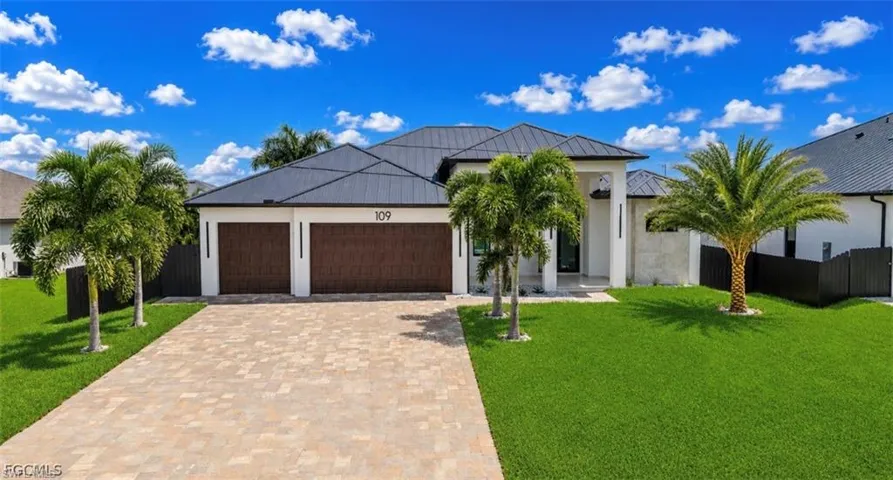 Modern single-story residence featuring a dark metal roof and light-colored stucco exterior