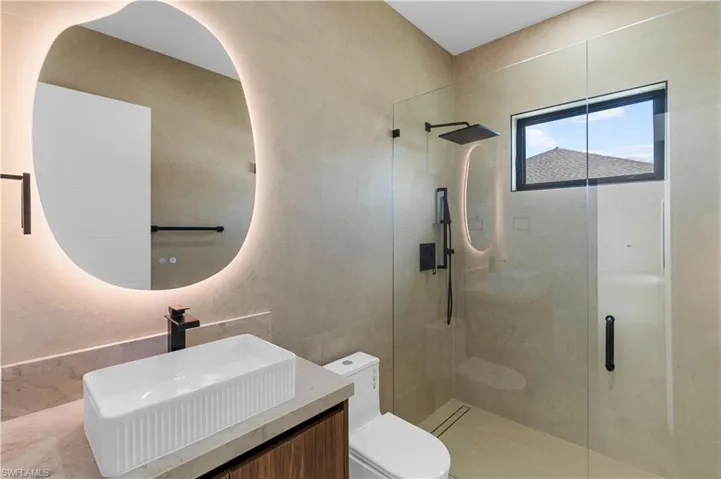 Bathroom with a shower stall, vanity, and tile walls