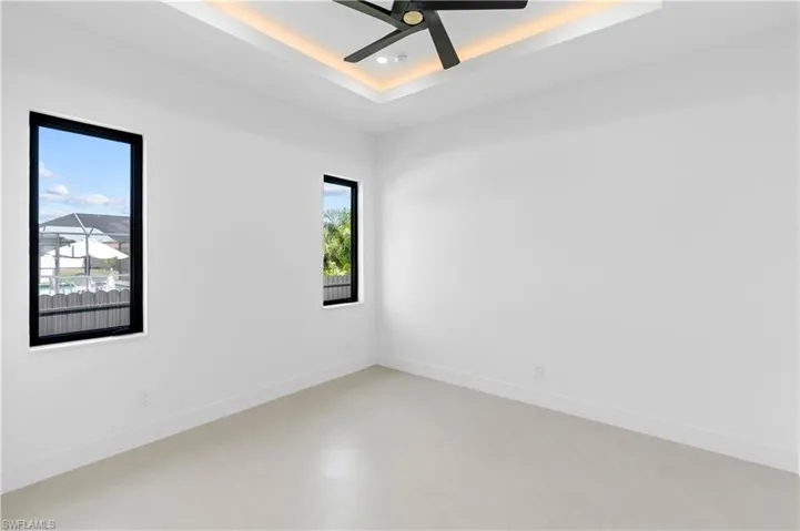 Spare room featuring a raised ceiling, finished concrete floors, and ceiling fan