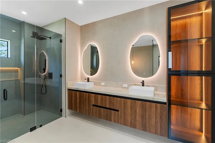 Bathroom featuring double vanity, a stall shower, and light tile patterned floors