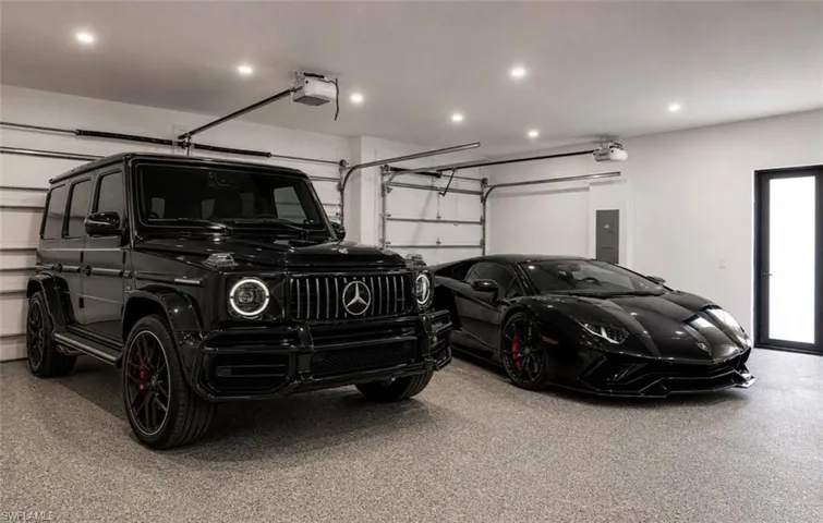 Spacious garage with light-toned epoxy flooring, two overhead garage doors, recessed ceiling lighting, and a modern side entry door