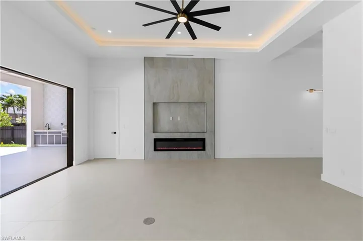 Unfurnished living room featuring ceiling fan, a large fireplace, and recessed lighting