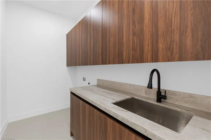 Kitchen with modern cabinets, light stone countertops, light tile patterned floors, and dark wood finish cabinets