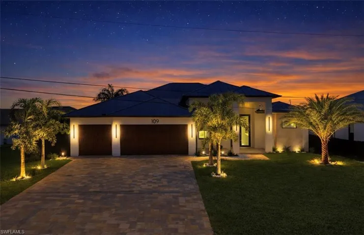 View of front facade featuring a garage, a front yard, driveway, stucco siding, and a metal roof