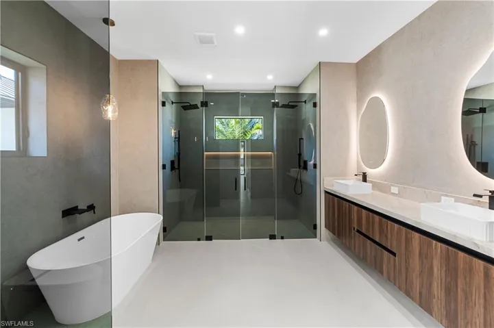 Full bath with double vanity, a stall shower, a freestanding tub, and recessed lighting