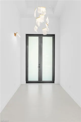 Empty room featuring french doors, a high tray ceiling, and light floors