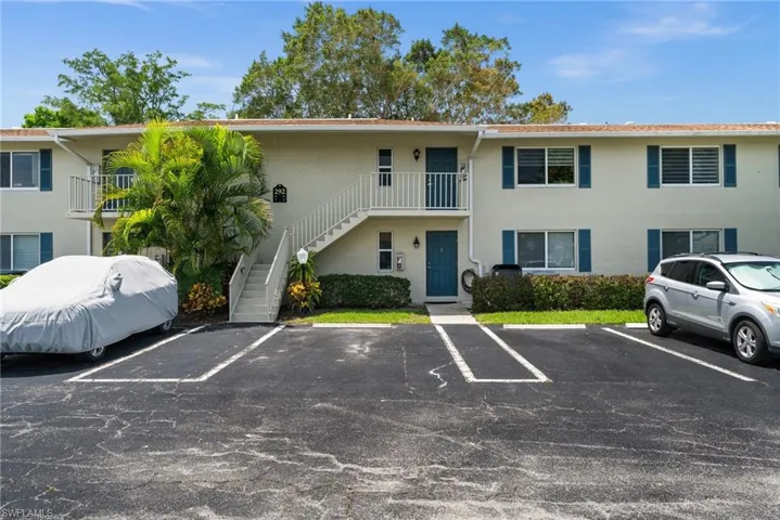 View of property featuring stairway and uncovered parking