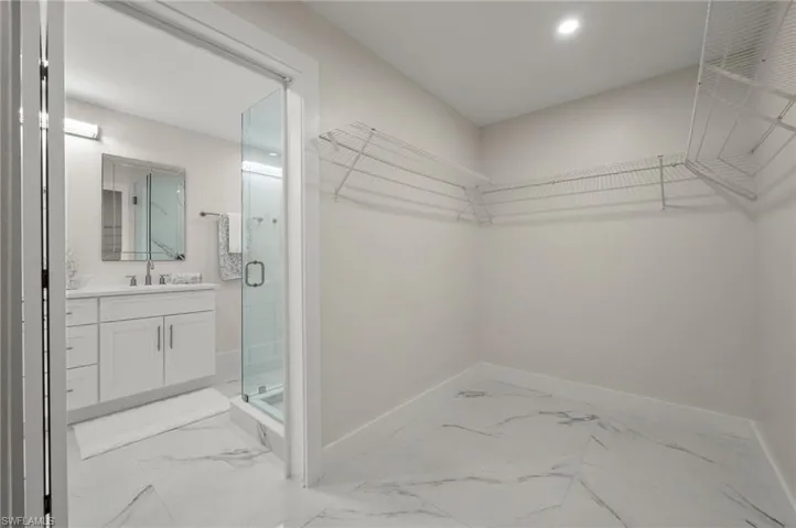 Walk in closet with light marble finish flooring and a sink