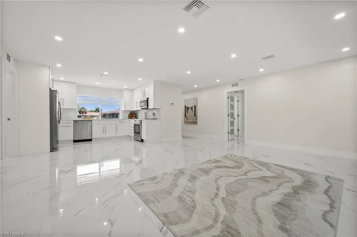 Unfurnished living room with light marble finish floors and recessed lighting