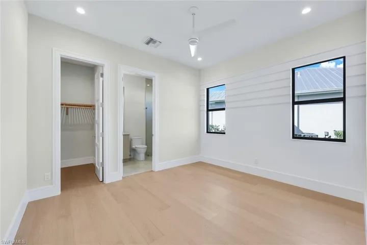 Unfurnished bedroom featuring a spacious closet, light wood-style floors, recessed lighting, and a ceiling fan