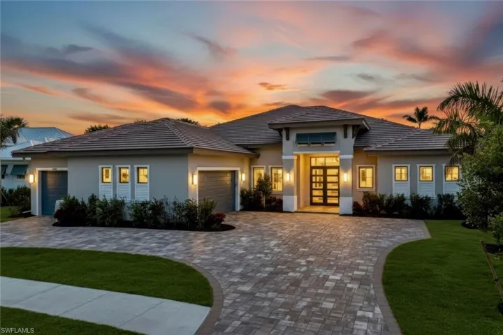 Prairie-style home with a yard, an attached garage, french doors, decorative driveway, and stucco siding