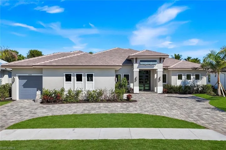 Prairie-style house with stucco siding, decorative driveway, french doors, and a front yard