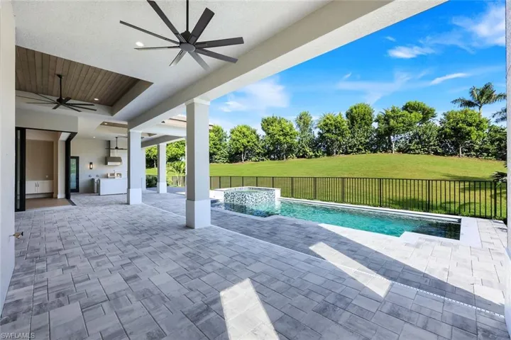 View of pool featuring a fenced backyard, a patio, an outdoor kitchen, and view of scattered trees