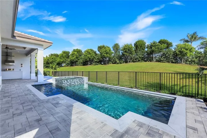 View of swimming pool featuring area for grilling, a fenced backyard, a patio, and view of scattered trees