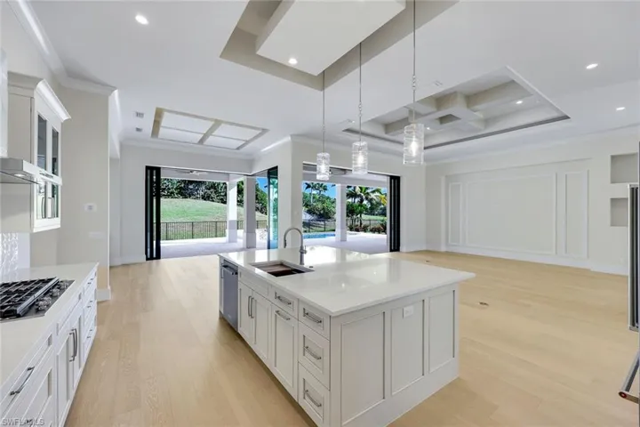 Kitchen with open floor plan, white cabinets, light wood-type flooring, coffered ceiling, and ornamental molding