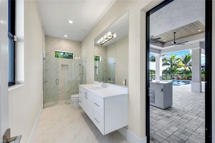 Bathroom featuring vanity, ceiling fan, a marble finish shower, recessed lighting, and light marble finish floors