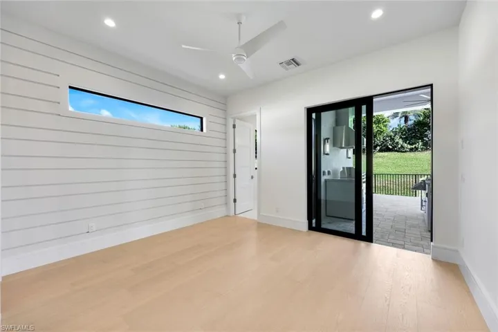 Spare room featuring wood finished floors, healthy amount of natural light, wooden walls, a ceiling fan, and recessed lighting