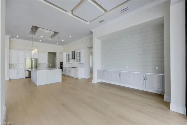 Unfurnished living room with crown molding, light wood-style flooring, a chandelier, and recessed lighting