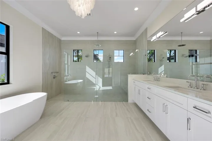 Bathroom with a soaking tub, a walk in shower, double vanity, and ornamental molding