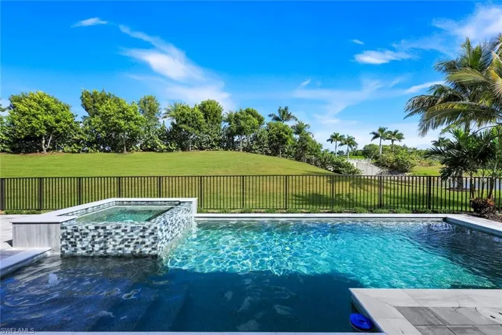 View of swimming pool featuring a fenced backyard and a pool with connected hot tub