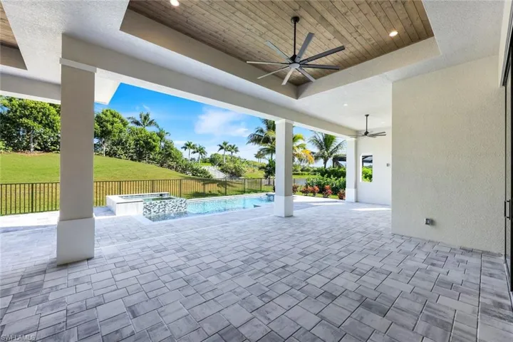 Fenced backyard with a patio, ceiling fan, and a pool with connected hot tub